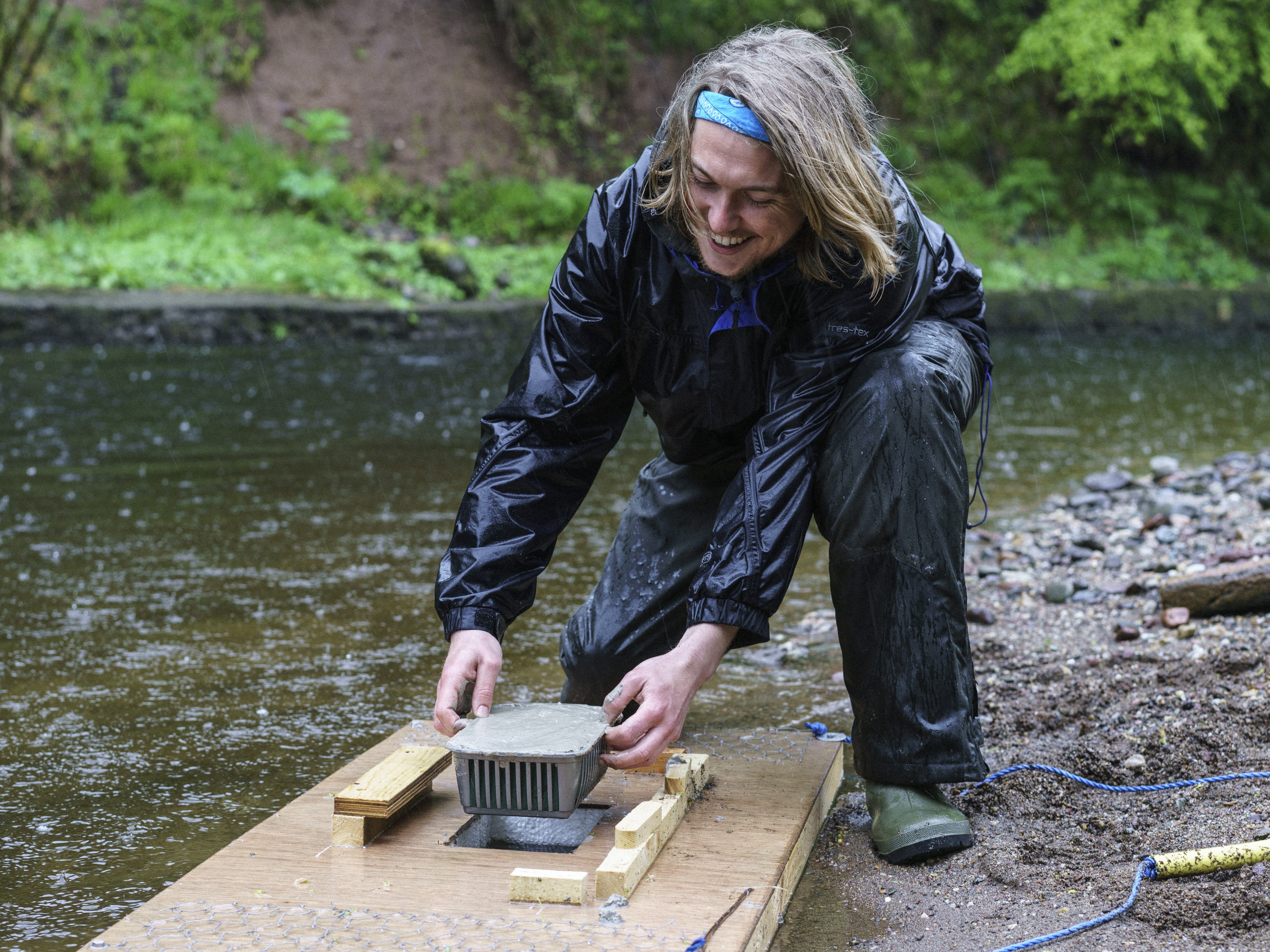 Volunteer putting clay monitoring pad on mink raft by river