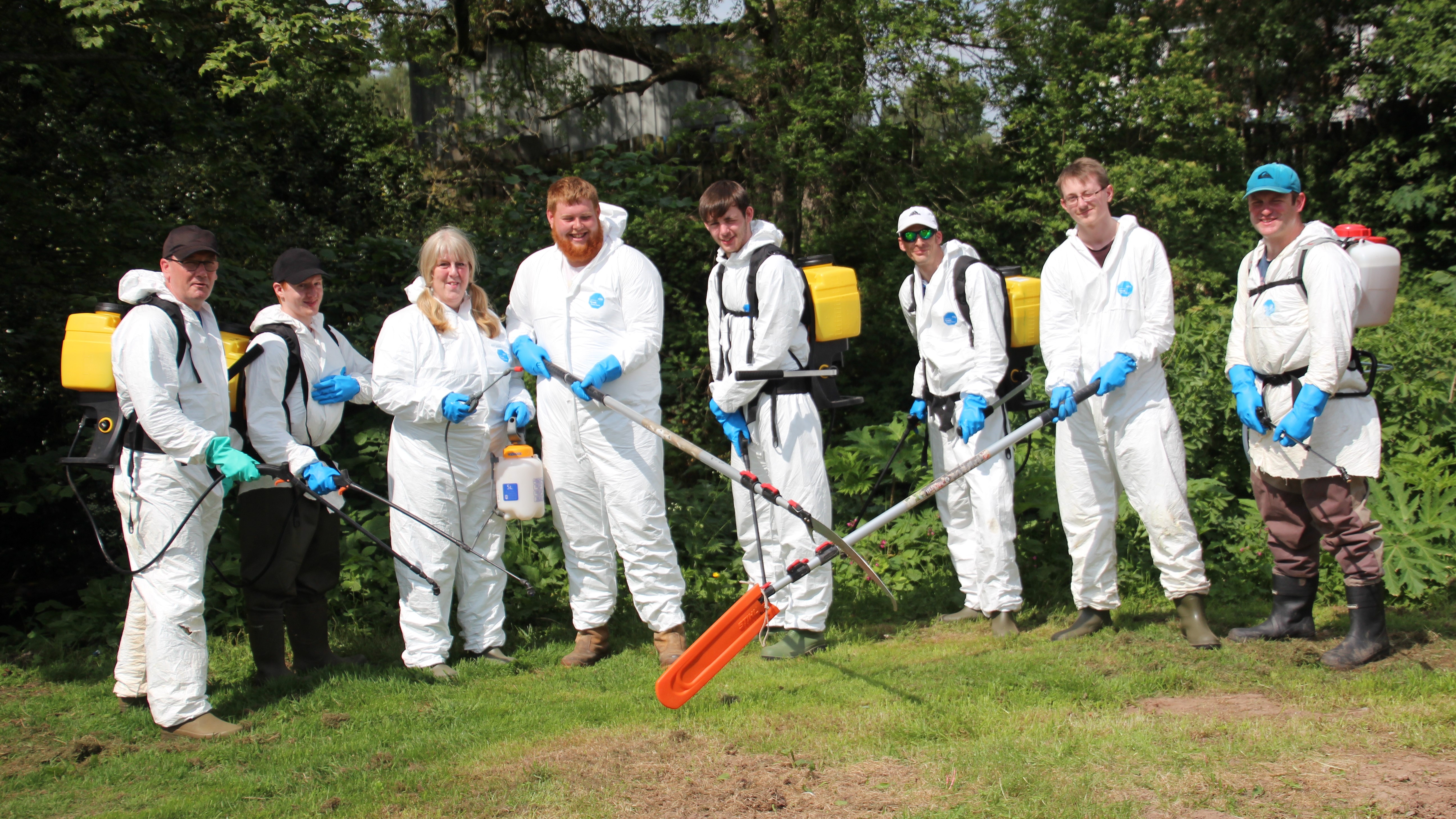 Group in spray suits with sprayers and extendable saws