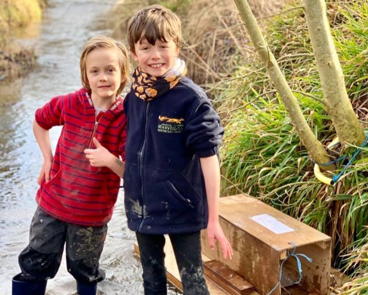 Boys in small river with mink raft