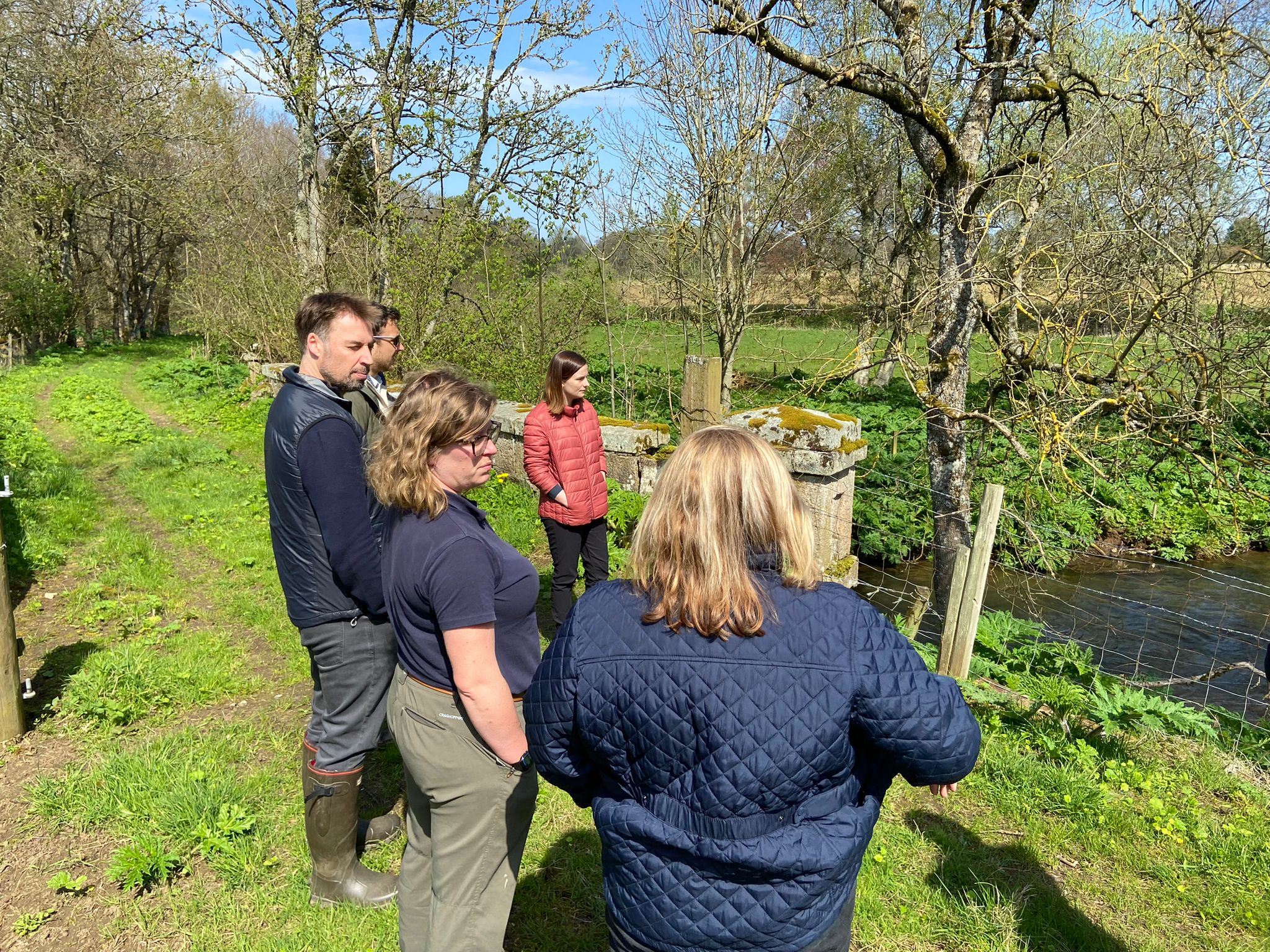 The group are standing by a river in discussion