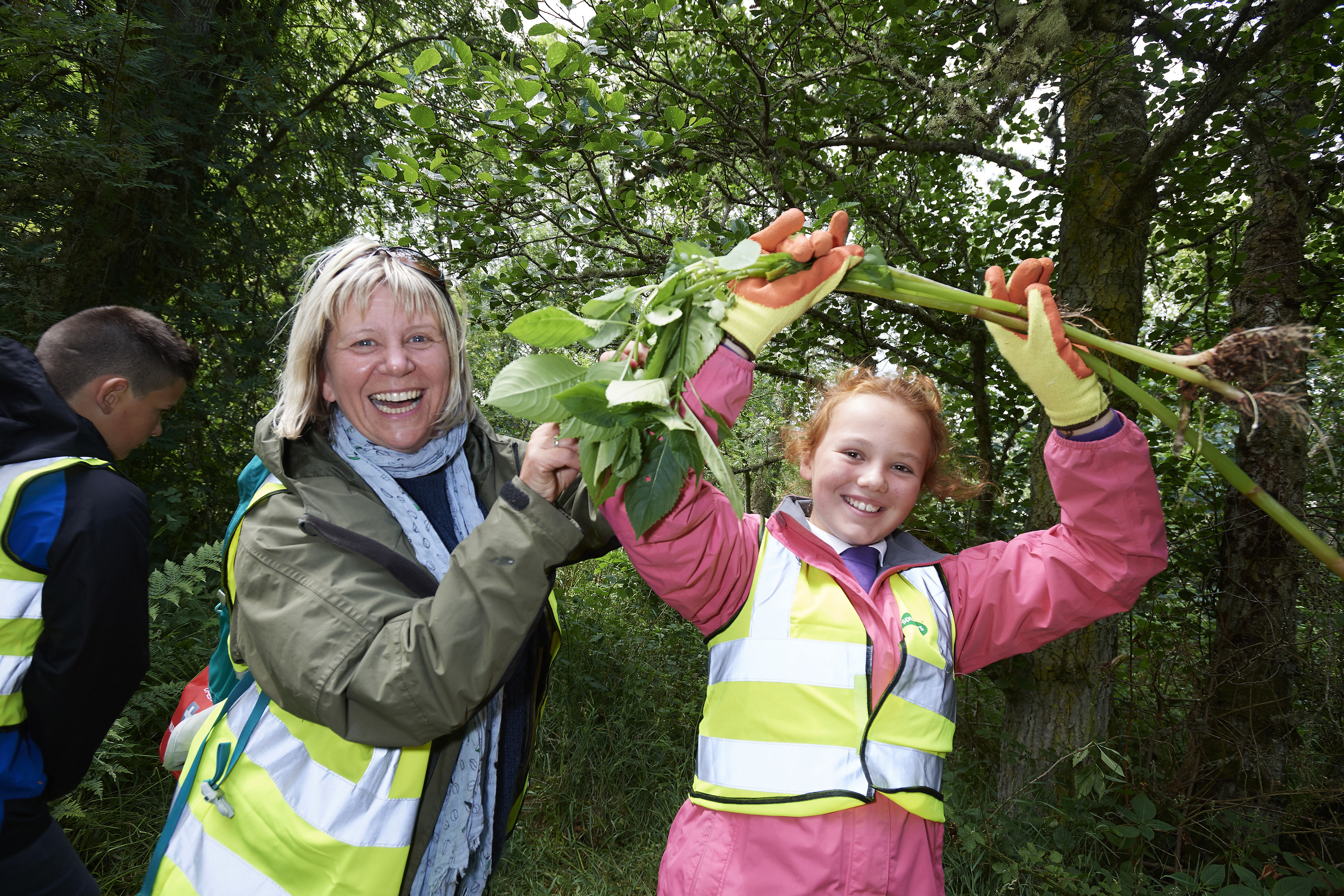 School pupil and teacher holding Himalayan balsam